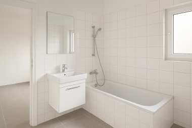 Modernes, frisch renoviertes Badezimmer mit weißen Fliesen, Badewanne und Wandwaschbecken.