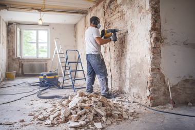 Handwerker entfernt alte Wandbeschichtung im Rahmen einer umfassenden Renovierung und Sanierung.