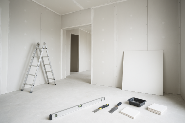 Innenraum im Ausbau mit montierten Gipskartonwänden, Aluminiumleiter und Werkzeugen – Trockenbauarbeiten im Fortschritt